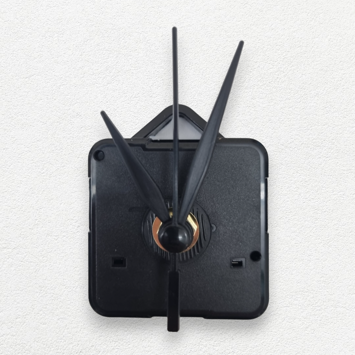 Black plastic silent quartz clock movement mechanism with three black hands on a white textured background.