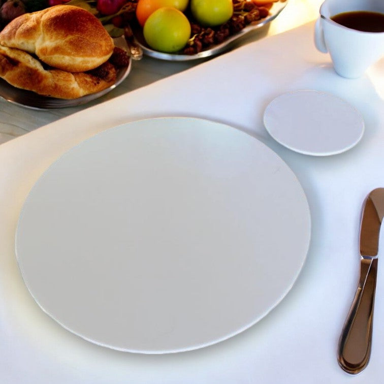Glossy, solid white round placemat and matching coaster on a white table setting.