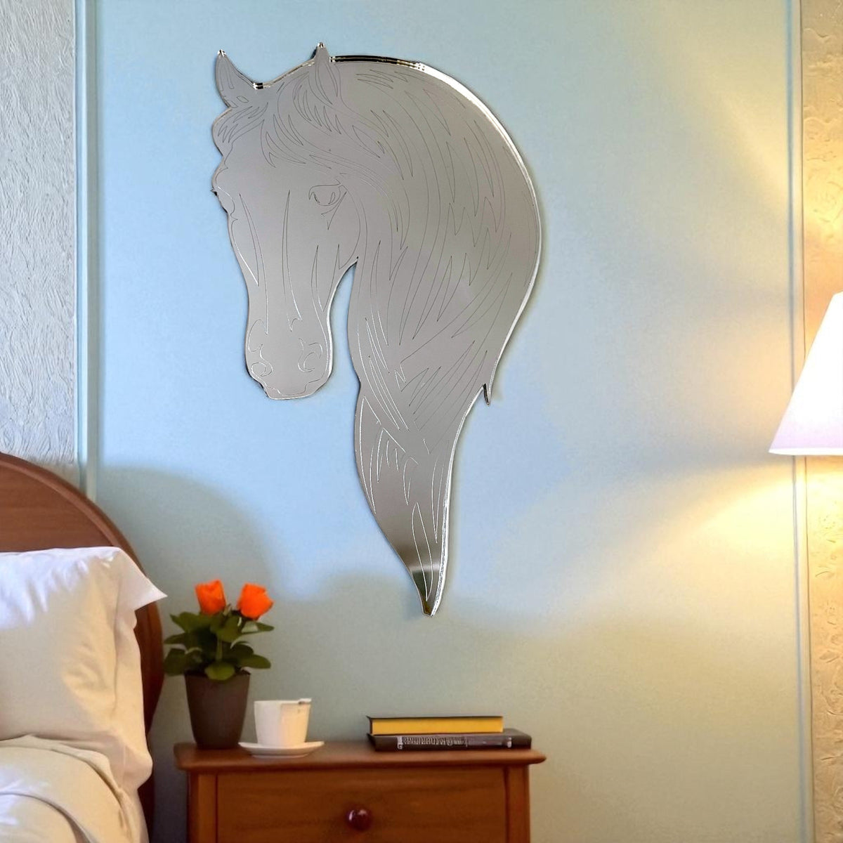 Silver horse-head wall mirror with etched mane and facial details, hanging on a blue wall.