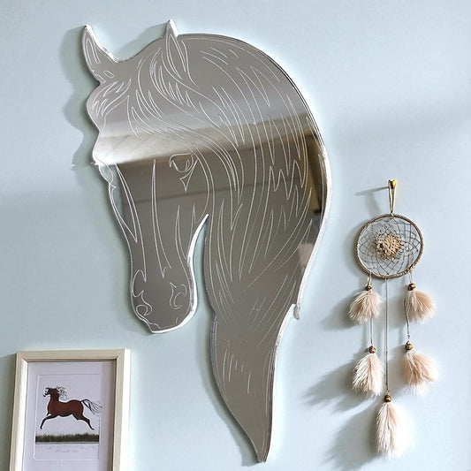 Etched horse head mirror hanging on a light blue wall, accompanied by a dreamcatcher and a framed horse print.