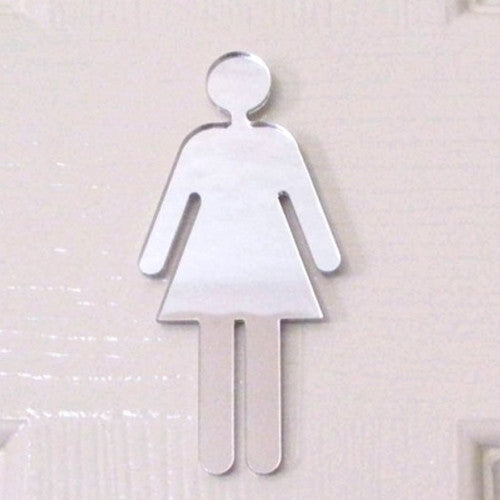 Mirrored silver acrylic female toilet sign shaped like a woman in a dress, mounted on a white surface.