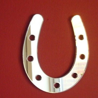 Silver horseshoe-shaped acrylic mirror with six nail holes, mounted on a solid red background.
