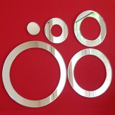 Five circular and ring-shaped silver mirrors of varying sizes on a red background.