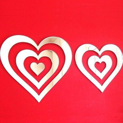 Two heart-shaped mirror wall decals with nested concentric cutouts on a red background.