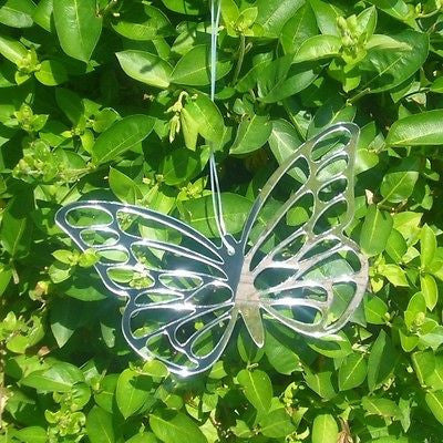 Silver butterfly-shaped garden mirror hanging against a background of green leaves.