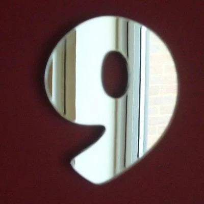 A silver number 9 shaped mirror against a dark red background.
