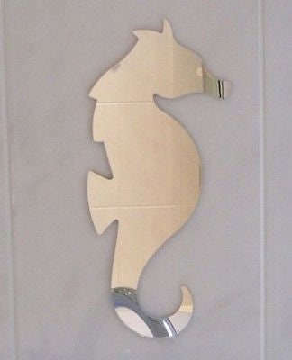 A silver seahorse-shaped wall mirror mounted on a light-colored wall.