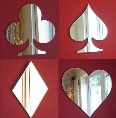 Four wall-mounted card suit mirrors in club, spade, diamond, and heart shapes on a red wall.