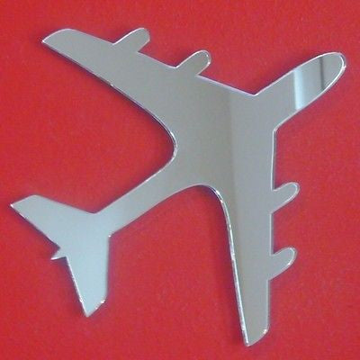 An aeroplane-shaped mirror with a reflective surface against a solid red background.