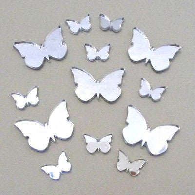 Twelve silver butterfly-shaped decorative mirrors of various sizes are arranged on a flat surface.