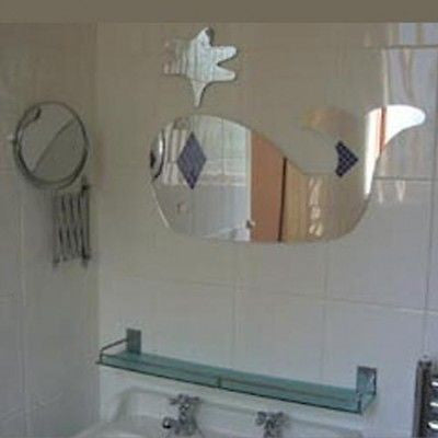 Whale and starfish shaped mirrors mounted on a tiled bathroom wall above a sink.