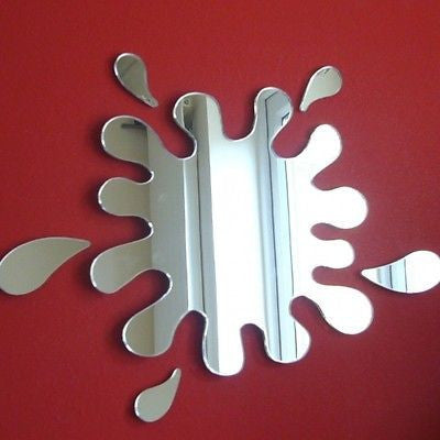 Splash Mirror mounted on a red wall, shaped like a liquid splash with separate droplet pieces.