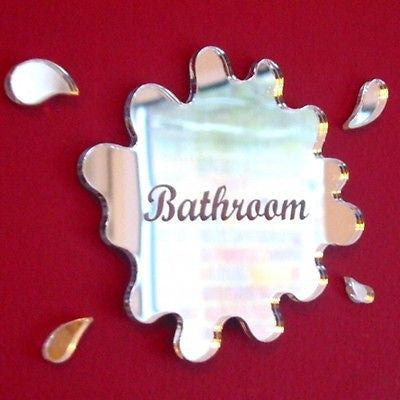 Mirrored puddle-shaped acrylic bathroom sign with engraved text, accompanied by four droplet mirrors on red.