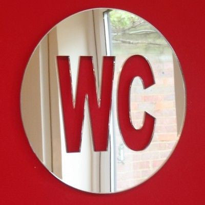 Round mirrored WC toilet sign on a red background.