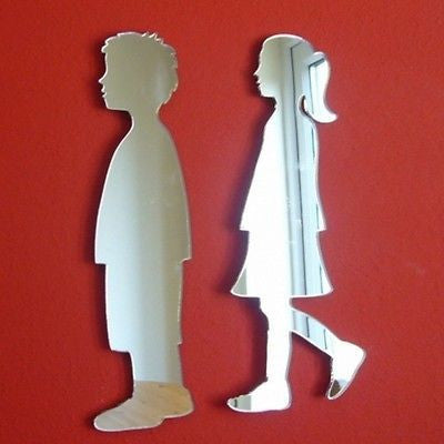 Two reflective wall mirrors shaped like a boy and a girl, mounted on a red wall.