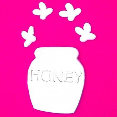 Honey pot and bee shaped mirrors on a bright pink background.