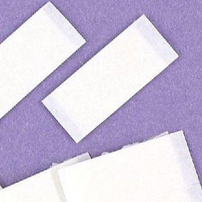 Rectangular white double-sided adhesive foam sticky pads on a purple background.