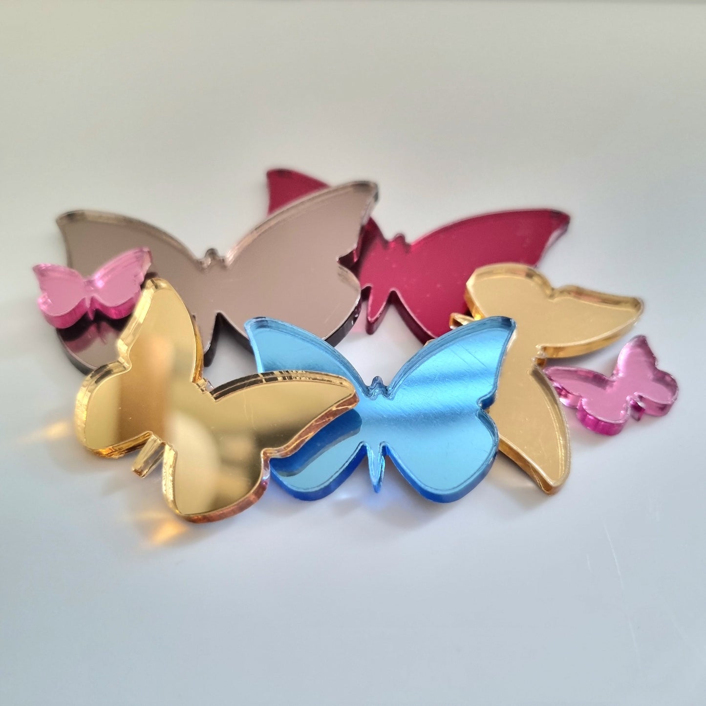 A cluster of colorful butterfly-shaped acrylic mirror pieces in gold, blue, pink, and rose gold.