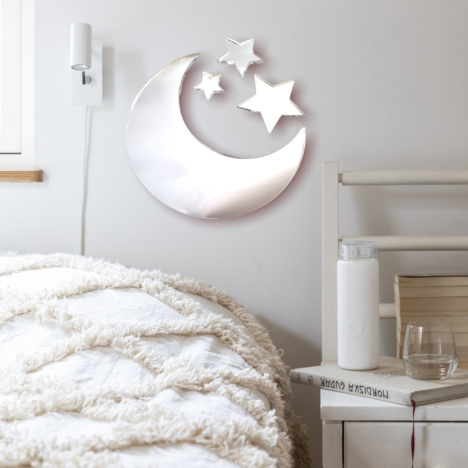 Crescent moon and three star-shaped wall mirrors mounted above a bed in a bedroom.