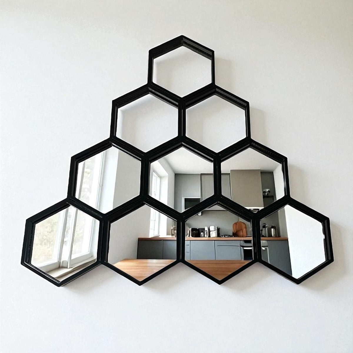 Black honeycomb hexagonal mirror with ten interlocking frames mounted on a white wall.