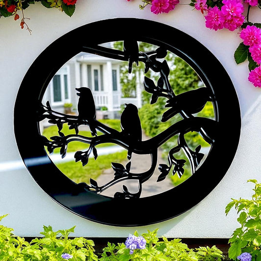 Round black garden mirror with a cutout silhouette of birds perched on leafy branches.