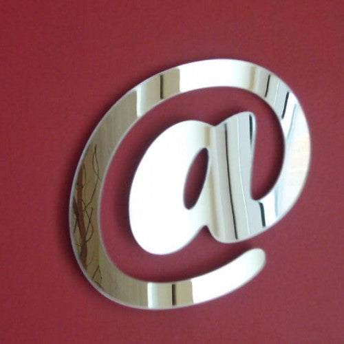 A fun, reflective mirror shaped like an @ sign, mounted on a solid red wall.