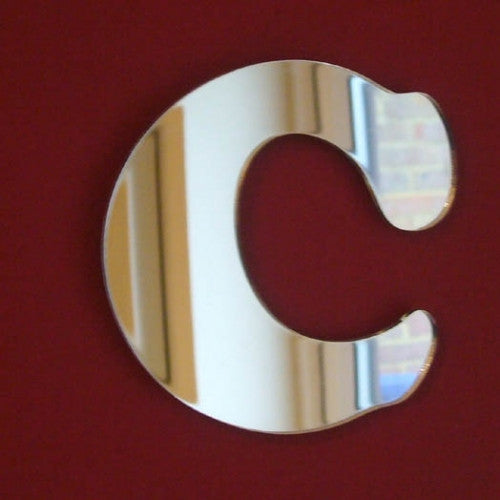Funky letter C mirror in reflective silver, mounted on a solid dark red wall.