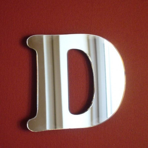 A silver, reflective letter D mirror mounted on a red wall.