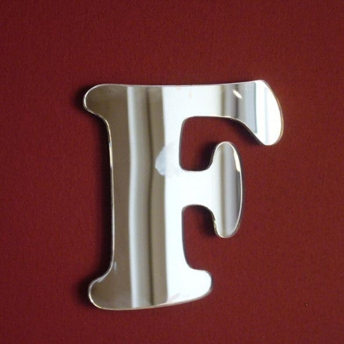 A silver, reflective mirror in the shape of a funky letter F against a red background.