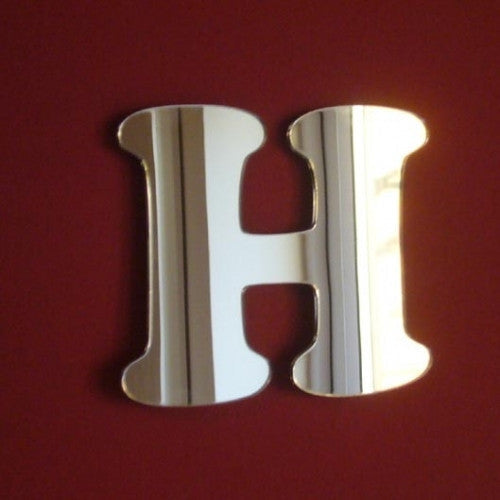 A silver reflective mirror in the shape of a stylized letter H against a dark red background.