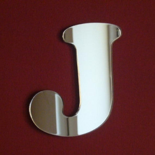 Reflective acrylic mirror in the shape of a funky letter J on a red background.