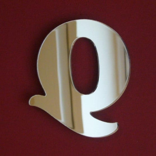 Reflective mirror cutout in the playful shape of the letter Q against a dark red background.