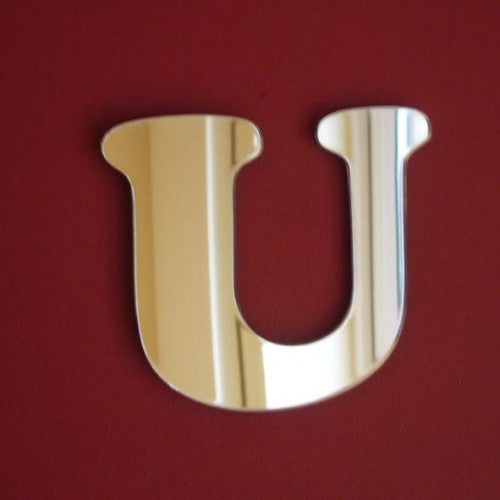 Funky letter U mirror in a reflective silver finish against a dark red background.