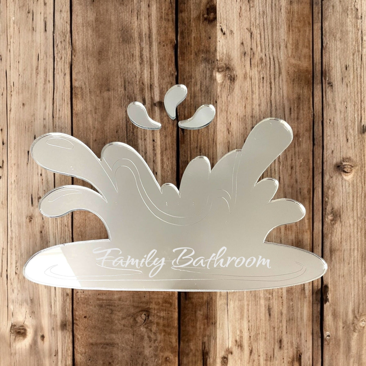 An etched water-splash shaped mirror with the text "Family Bathroom" on a wooden background.