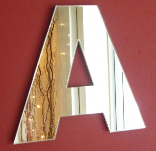 A contemporary letter A shaped mirror mounted on a red wall.