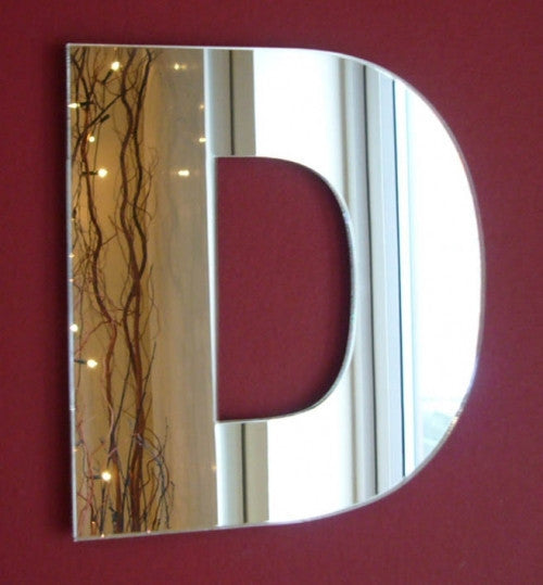 Contemporary letter D mirror mounted on a solid dark red wall.