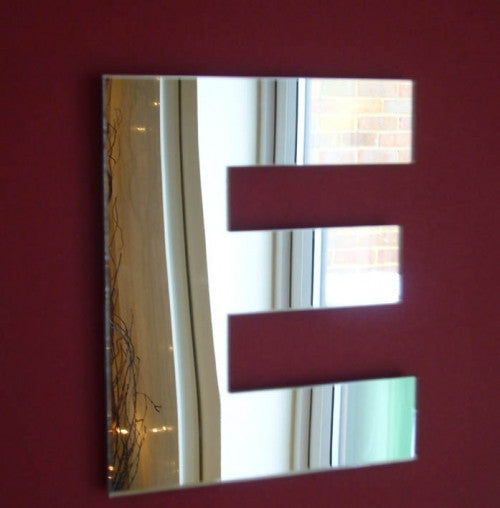 A square wall mirror shaped like the letter E mounted on a dark red wall.