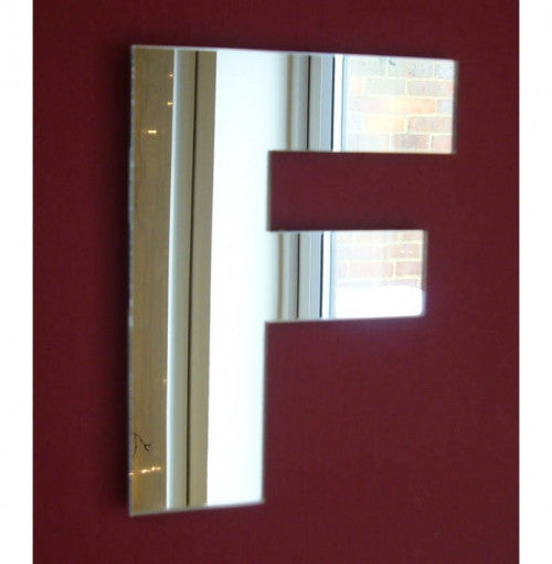 Contemporary letter F mirror mounted on a solid dark red wall.