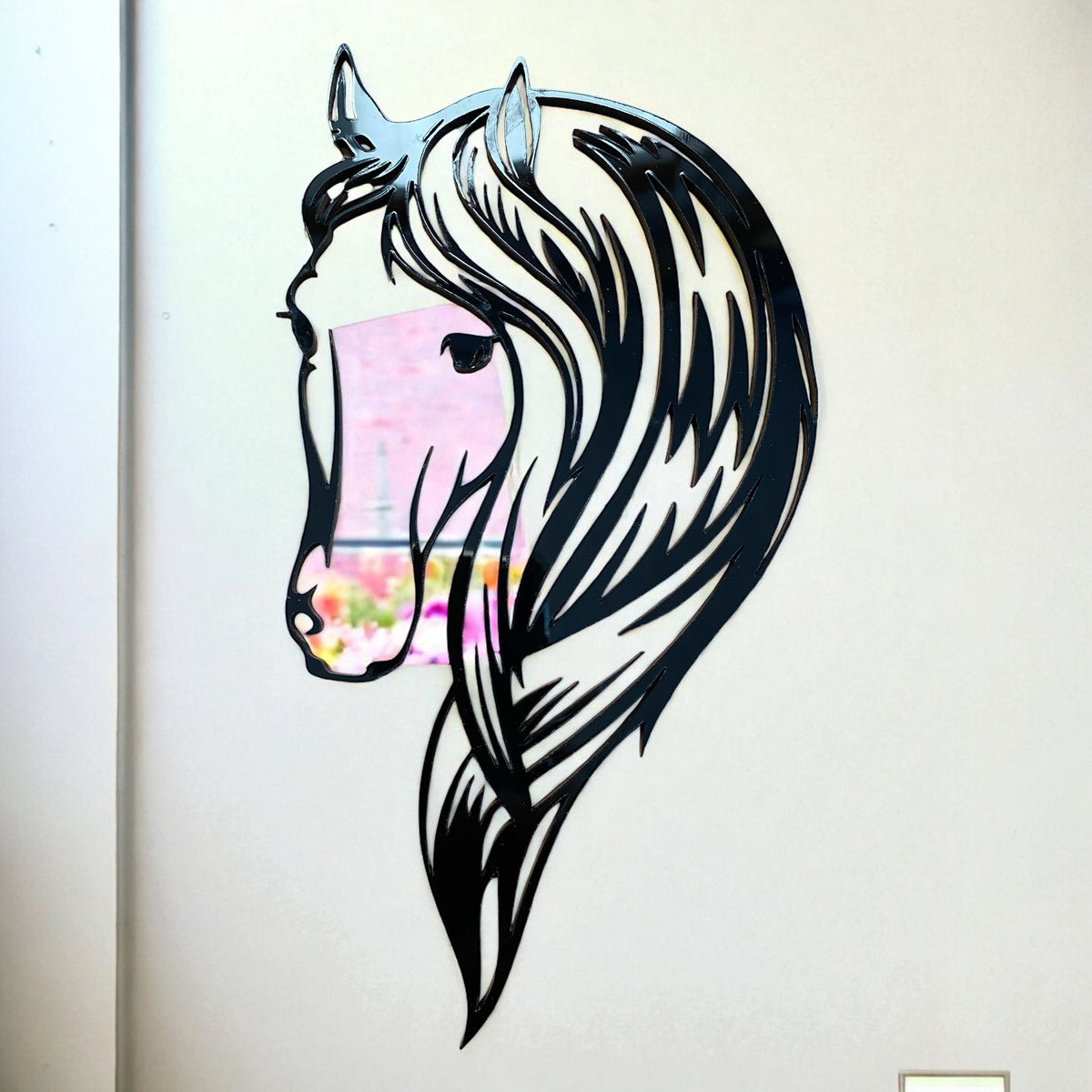 Black acrylic horse head garden mirror with a stylized mane, mounted on a plain wall.