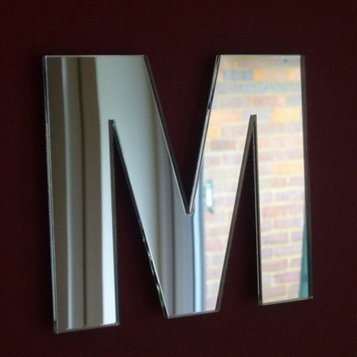 Contemporary letter M-shaped wall mirror with a reflective glass finish.