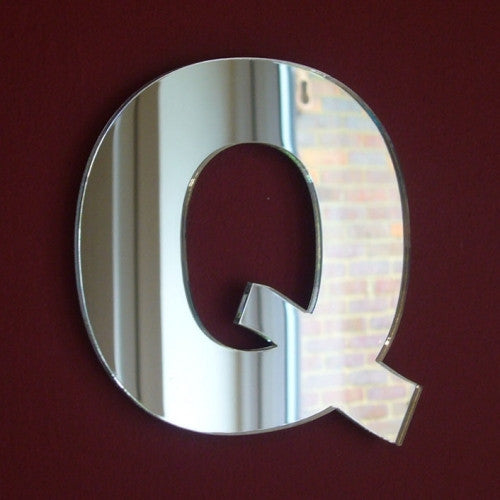 Contemporary letter Q shaped mirror mounted on a dark red wall.