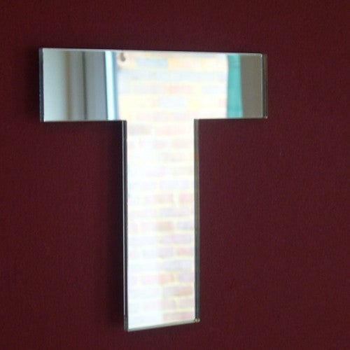 Contemporary letter T wall mirror with a reflective glass surface, mounted on a dark red wall.