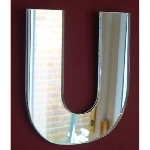 Contemporary letter U mirror mounted on a dark red wall, featuring a sleek, reflective surface.