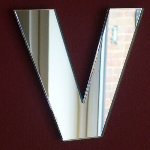 Contemporary letter V-shaped wall mirror with bevelled edges on a dark red wall.