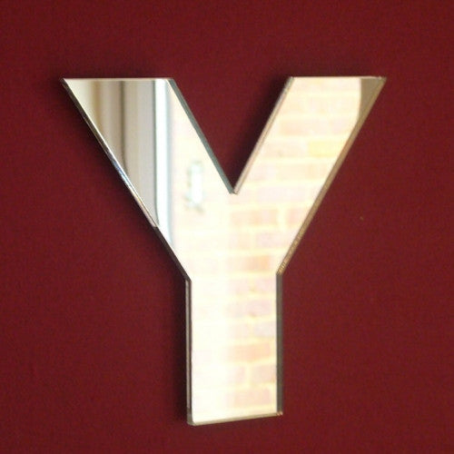A reflective letter Y mirror mounted on a solid dark red wall.