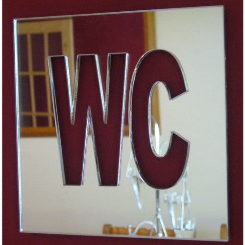 Square mirrored WC toilet sign with bold cutout letters on a dark red background.