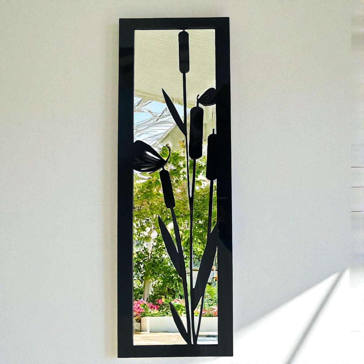 Rectangular black-framed garden mirror with a black metal overlay depicting bulrushes and butterflies.