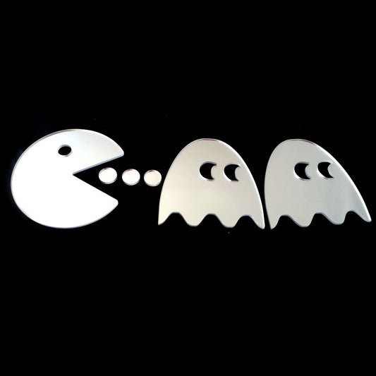 Pac-Man and ghost-shaped silver mirrors with small dots on a black background.