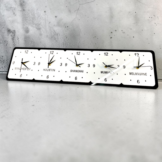 Black and white rectangular wall clock with five square clock faces labeled Manchester, Houston, Shanghai, Mumbai, Melbourne.