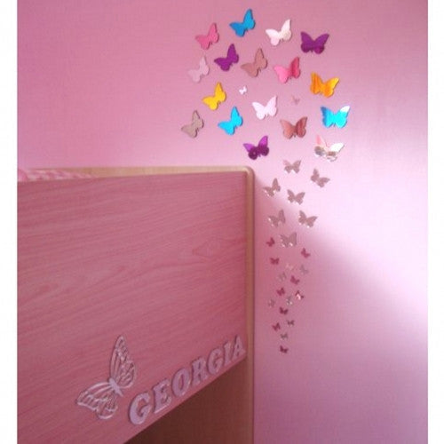 Assorted colorful butterfly mirror shapes arranged in a swirling pattern on a pink wall.